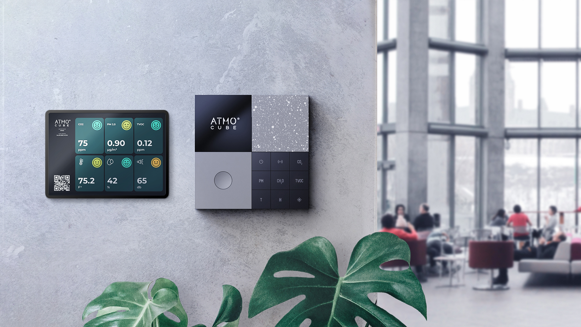 Atmocube monitor on an office wall next to a tablet showing air quality data