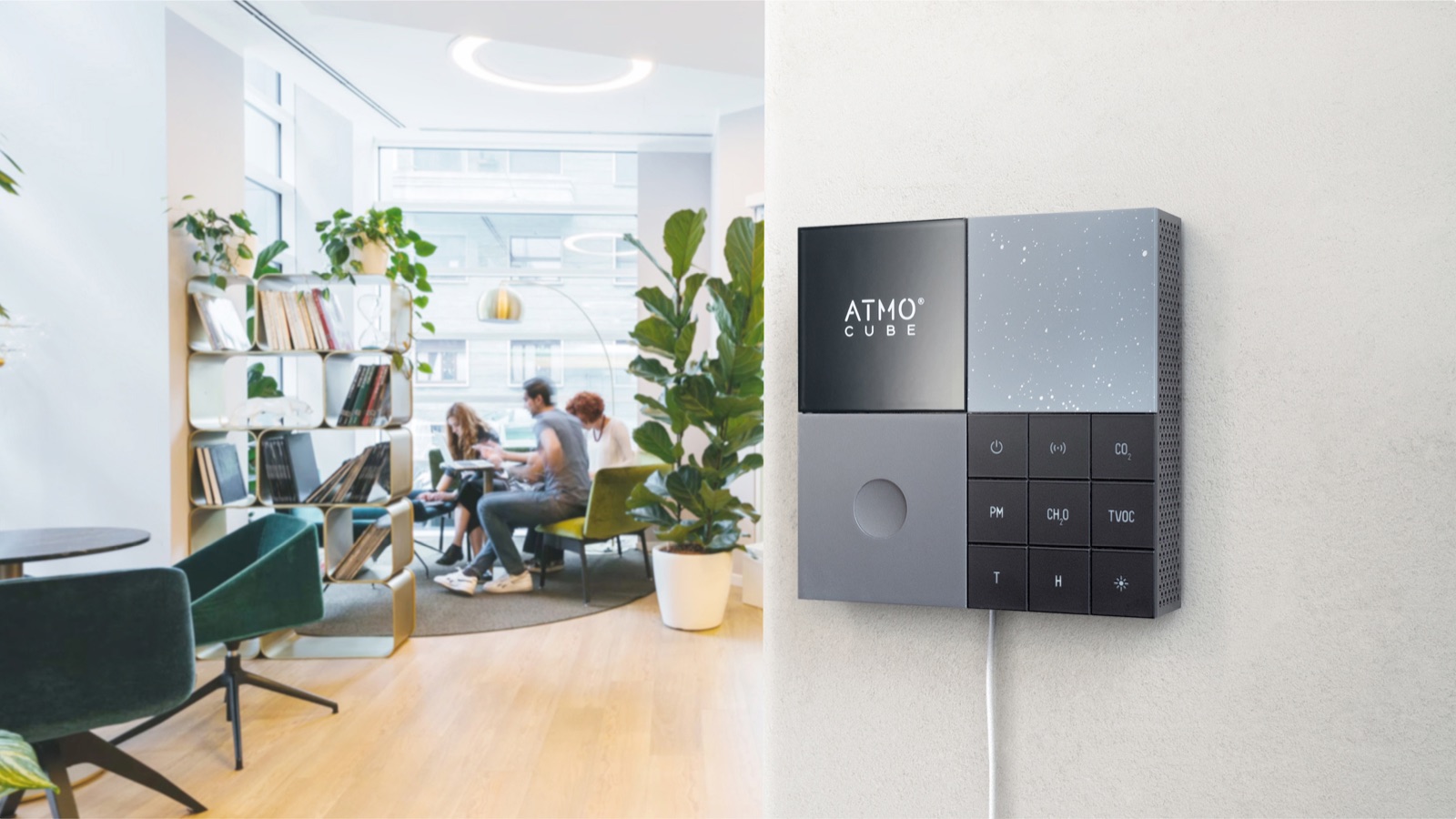 Atmocube indoor air quality monitor on an office wall, with buttons for CO₂, PM, formaldehyde (CH₂O), TVOC, temperature and humidity