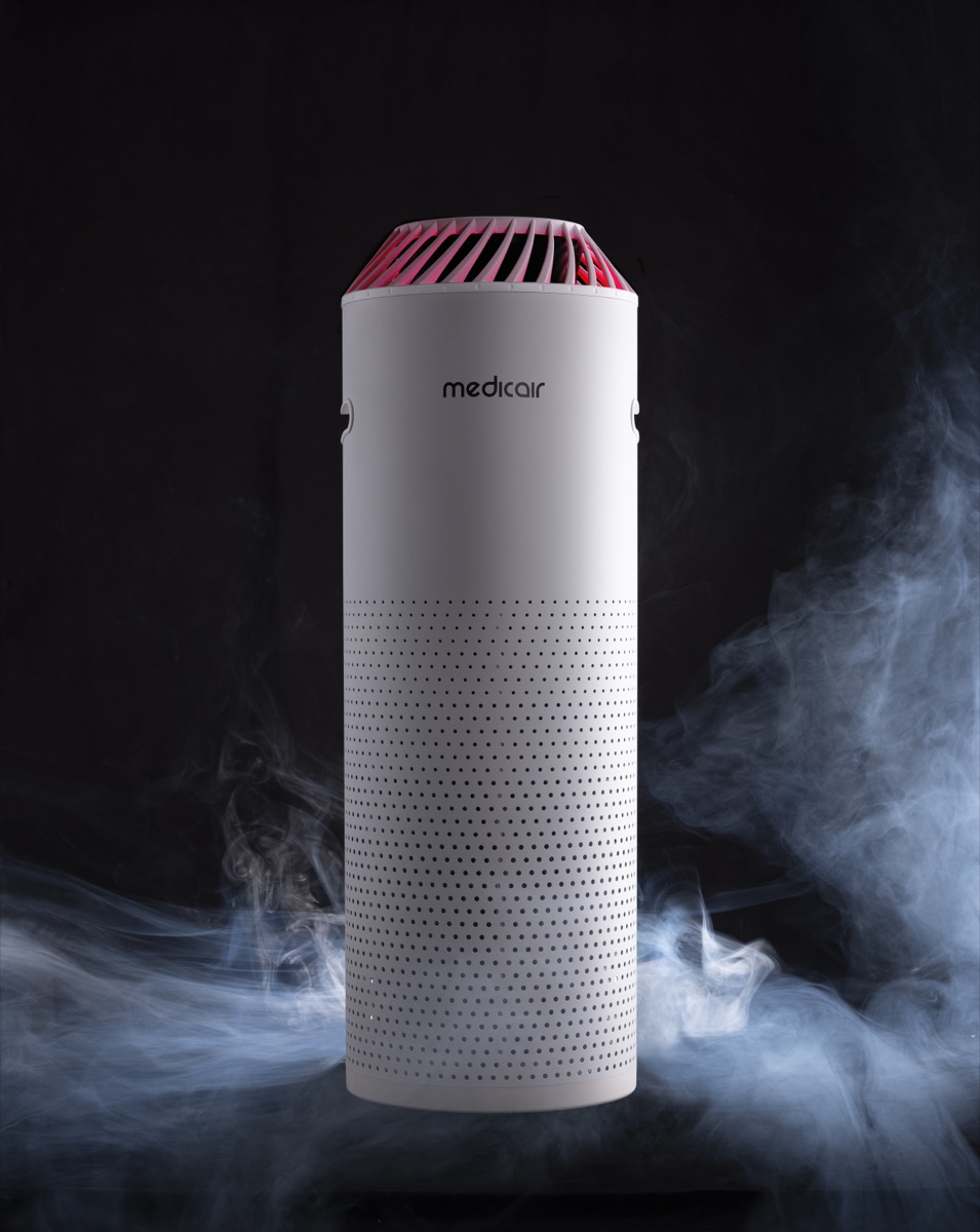 MedicAir Pro air purifier with a red-lit top standing in drifting smoke on a black background
