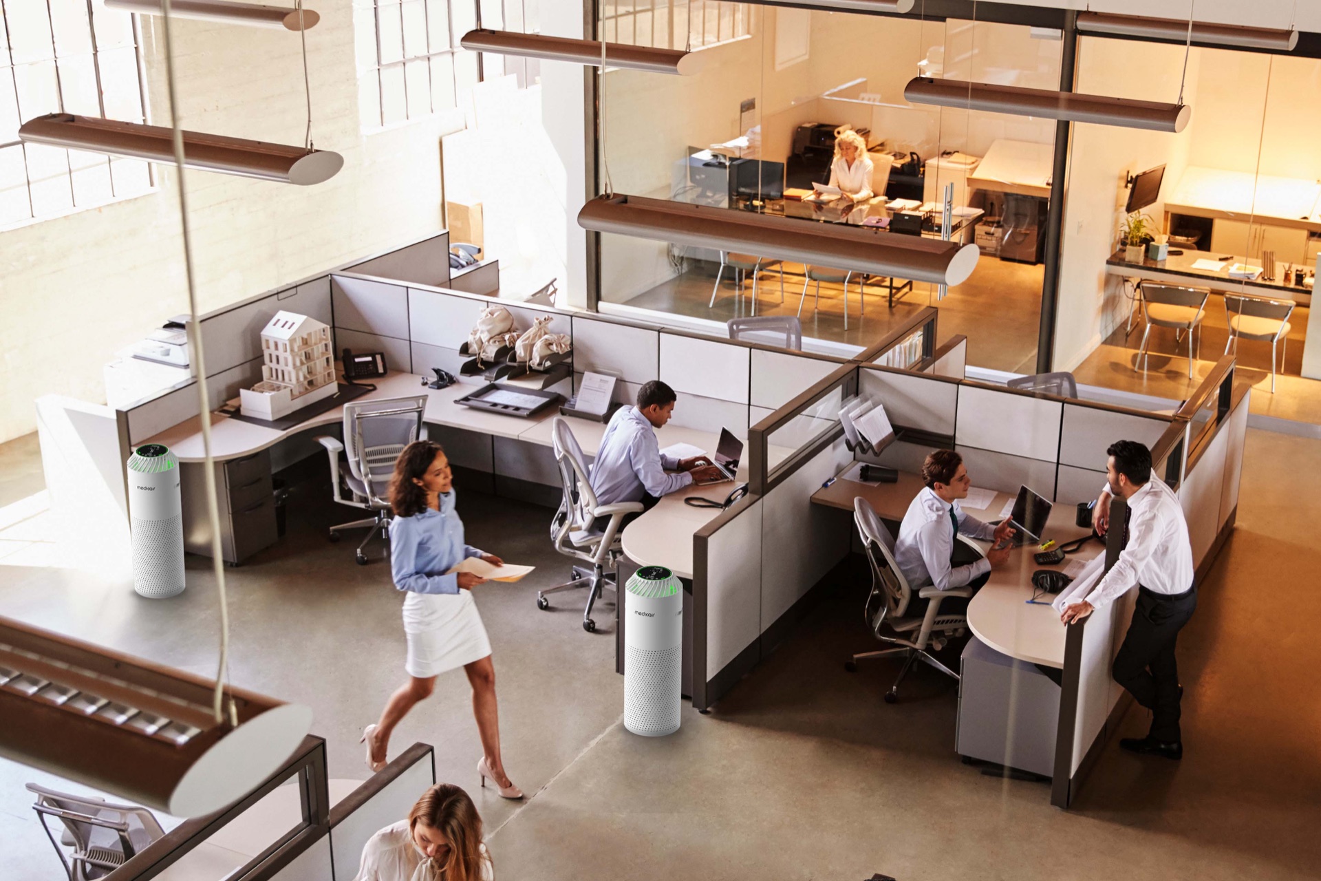 Two MedicAir Pro air purifiers standing among desks in a busy open-plan office, seen from above