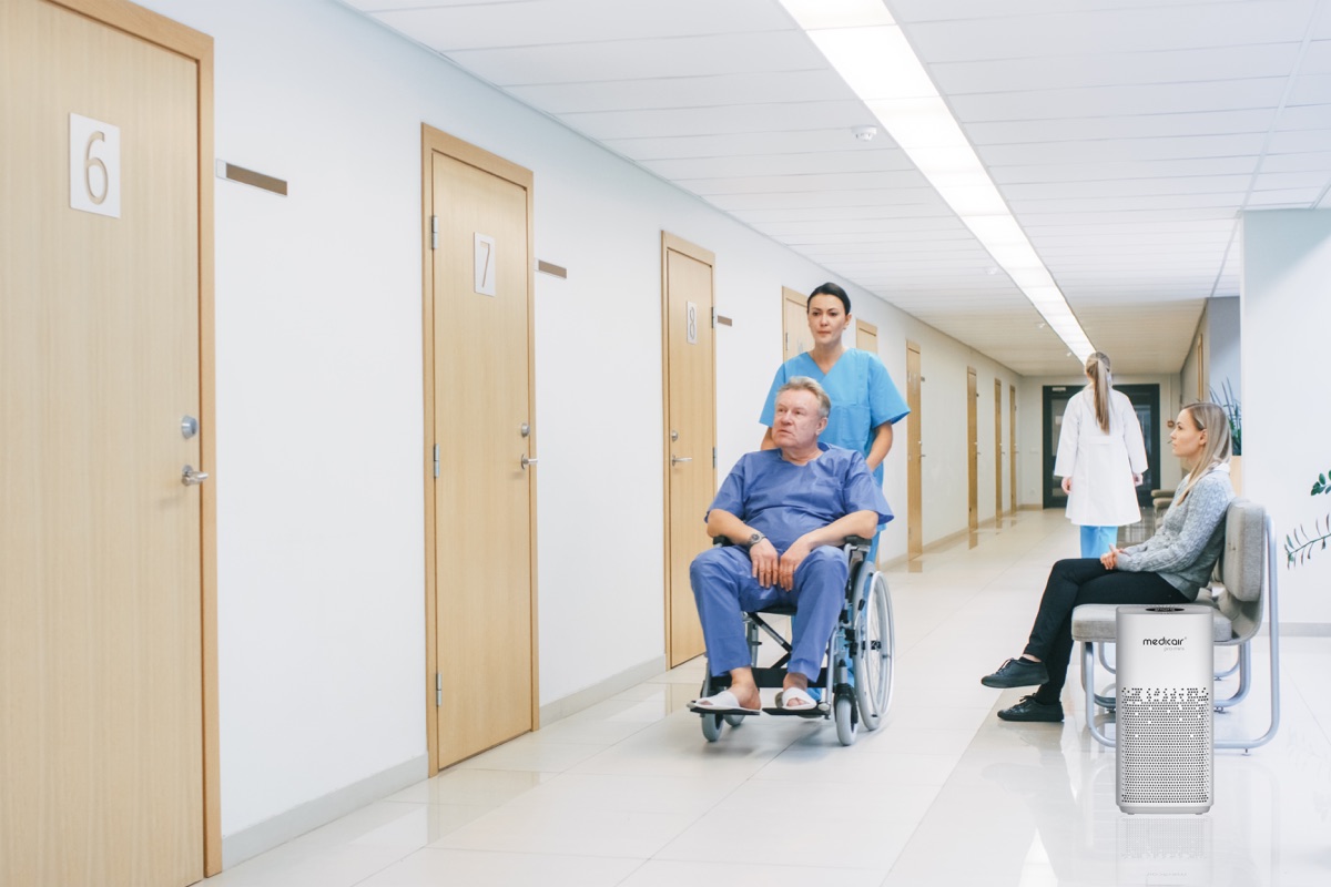MedicAir Pro Mini air purifier in a hospital corridor as a nurse pushes a patient in a wheelchair