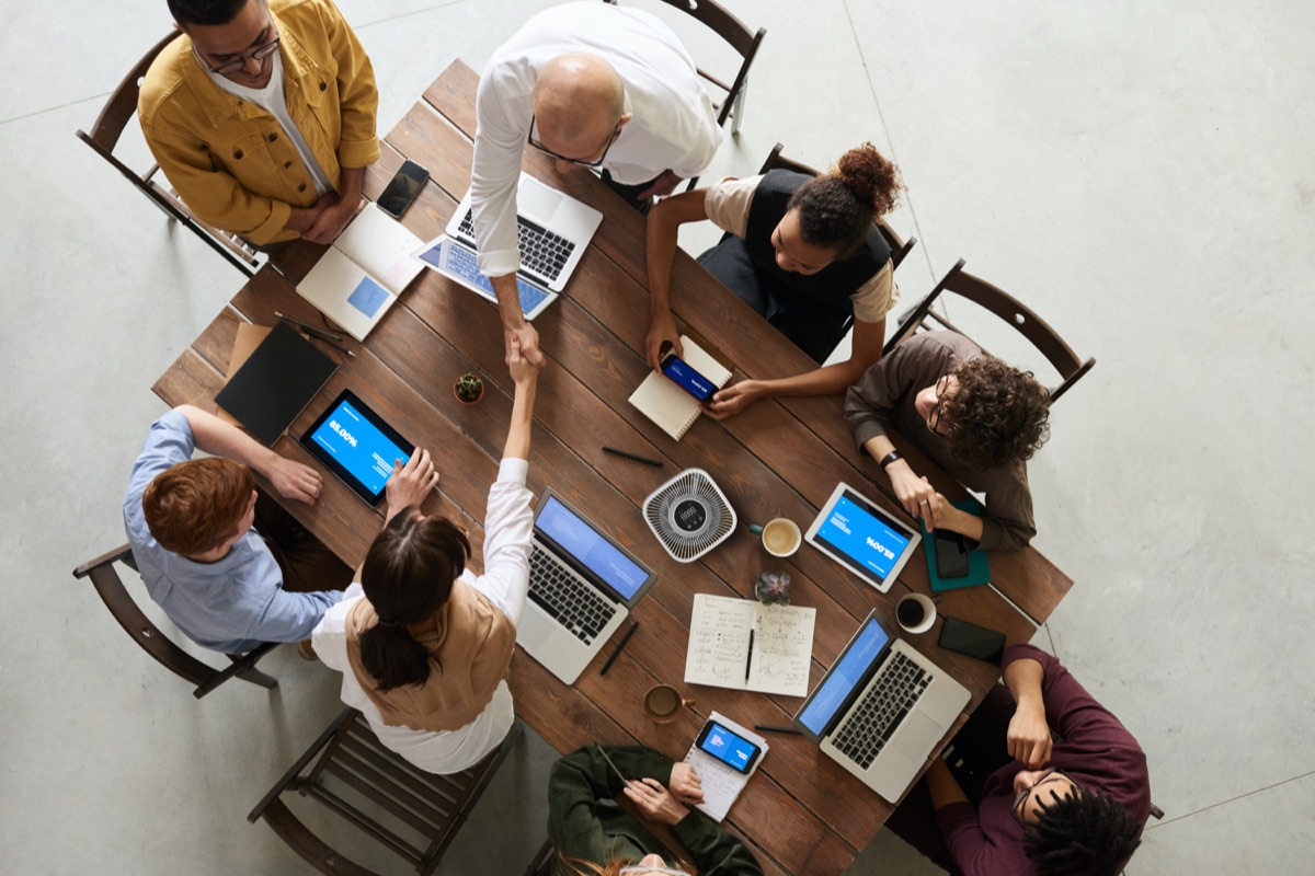 Overhead view of a team meeting at a wooden table with laptops and a MedicAir Pro Mini in the centre